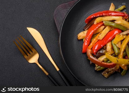 Delicious vegetables steamed peppers, asparagus beans and potatoes sliced with soy sauce on a dark concrete background