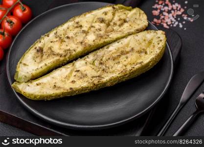 Delicious zucchini cut into two halves baked with salt, spices and herbs on a dark concrete background