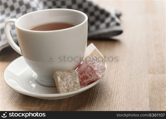 delight yellow and red on a plate sprinkled with powdered sugar with tea in a Cup