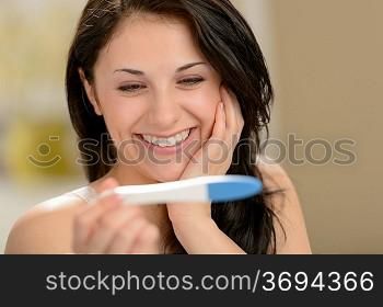 Delighted and surprised woman holding pregnancy test
