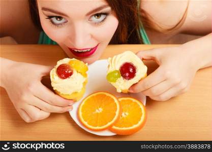 Delighted woman hiding behind table sneaking and eating delicious cake with sweet cream and fruits on top. Appetite and gluttony concept.. Woman taking delicious sweet cake. Gluttony.