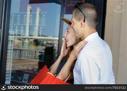 delighted young couple looking in shop window