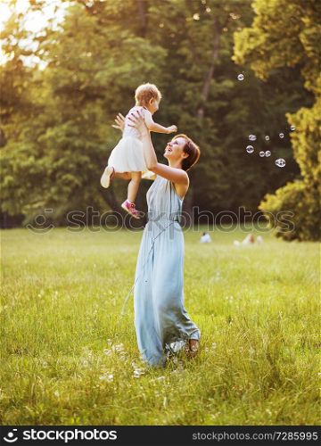 Delighted young mother tossing her lovely child