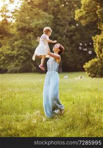 Delighted young mother tossing her lovely child