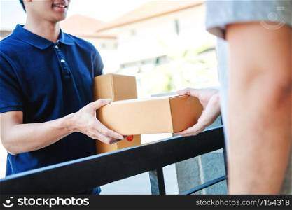 Delivery Asian man service with boxes in hands standing in front of Customer&rsquo;s house doors