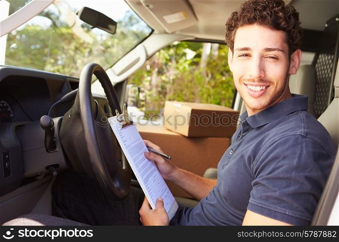 Delivery Driver Sitting In Van Filling Out Paperwork