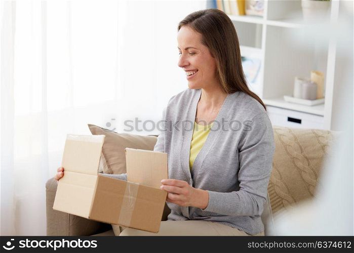 delivery, mail and people concept - smiling middle-aged woman opening parcel box at home. smiling woman opening parcel box at home