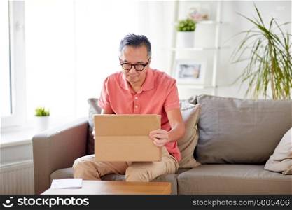 delivery, mail, consumerism and people concept - man opening parcel box at home. man opening parcel box at home