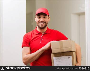 delivery, mail, people and shipment concept - happy man in red uniform with parcel boxes in corridor. delivery man with parcel boxes in corridor