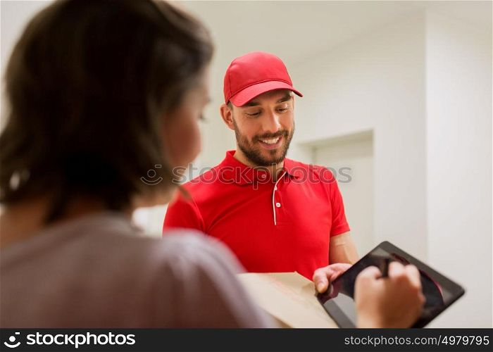 delivery, mail, people and shipping concept - happy man delivering parcel box and customer signing on tablet pc computer at home. delivery man with box and tablet pc at customer