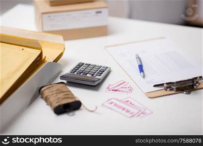 delivery, mail service and shipment concept - calculator, clipboard, rope and envelopes at post office. calculator, clipboard and envelopes at post office