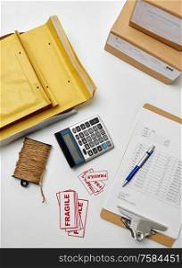 delivery, mail service and shipment concept - calculator, clipboard, rope with fragile stickers and envelopes at post office. calculator, clipboard and envelopes at post office