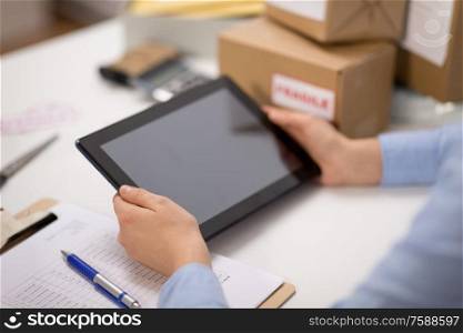 delivery, mail service, people and shipment concept - close up of hands with tablet pc computer, parcel boxes and form on clipboard at post office. hands with tablet pc and clipboard at post office