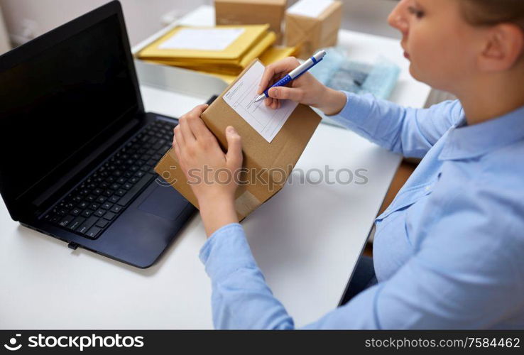 delivery, mail service, people and shipment concept - close up of woman filling postal form at office. close up of woman filling postal form at office