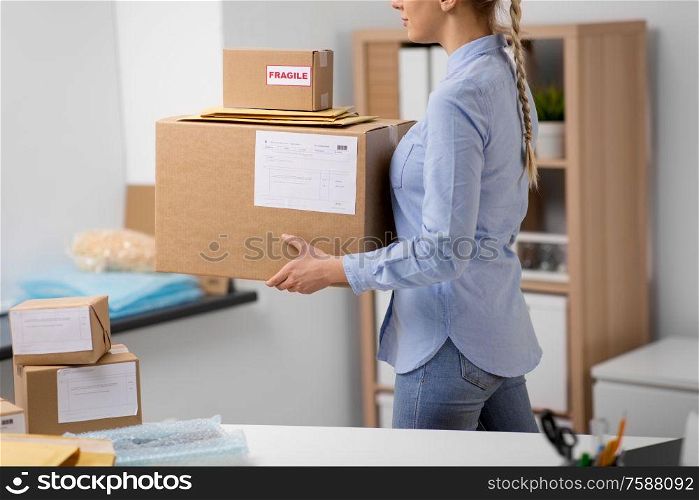delivery, mail service, people and shipment concept - close up of woman walking with parcel boxes and envelopes at post office. woman walking with parcels at post office