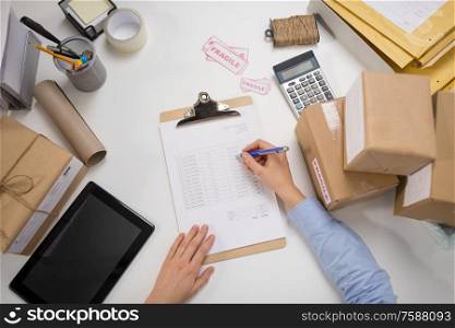 delivery, mail service, people and shipment concept - close up of woman with parcel boxes and clipboard working at post office. woman with parcels and clipboard at post office