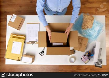 delivery, mail service, people and shipment concept - close up of woman packing fragile parcel boxes at post office. woman packing fragile parcel boxes at post office
