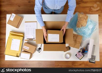 delivery, mail service, people and shipment concept - close up of woman packing parcel boxes at post office. woman packing parcel boxes at post office