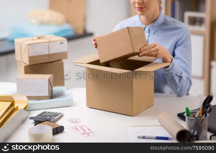 delivery, mail service, people and shipment concept - close up of woman packing parcel box at post office. woman packing parcel box at post office