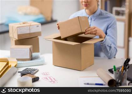 delivery, mail service, people and shipment concept - close up of woman packing parcel box at post office. woman packing parcel box at post office