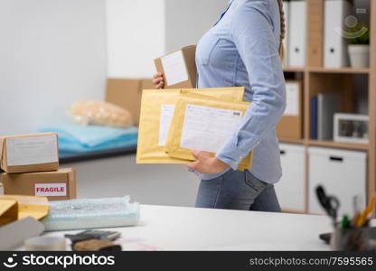 delivery, mail service, people and shipment concept - close up of woman walking with parcel box and envelopes at post office. woman walking with parcels at post office