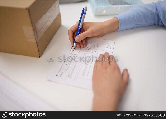delivery, mail service, people and shipment concept - close up of woman filling postal form at office. close up of woman filling postal form at office