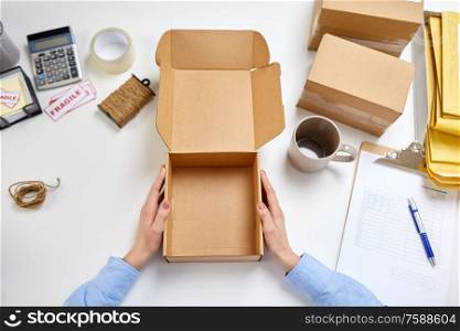 delivery, mail service, people and shipment concept - female hands with empty parcel box and mug at post office. hands with empty parcel box and mug at post office