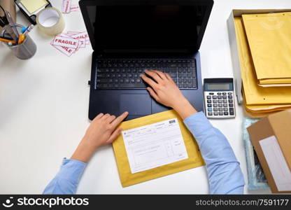 delivery, mail service, people and shipment concept - female hands with laptop computer and envelope parcel with postal form on it at post office. hands with laptop and envelope at post office