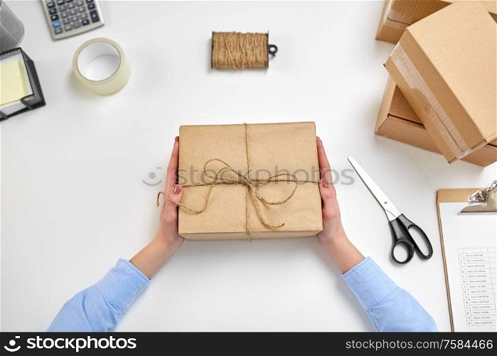 delivery, mail service, people and shipment concept - female hands with parcel box tied by rope at post office. hands with parcel box tied by rope at post office