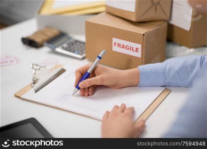 delivery, mail service, people and shipment concept - hands with clipboard filling checklist at post office. hands with clipboard and parcels at post office
