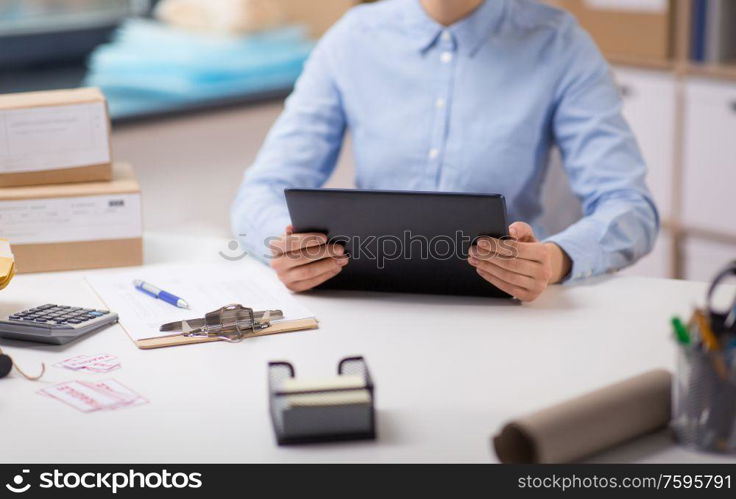 delivery, mail service, people and shipment concept -woman with tablet pc computer, parcel boxes and form on clipboard at post office. woman with tablet pc and clipboard at post office