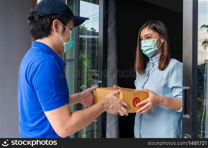 Delivery man delivering a parcel box to customer woman at home, people must wear a mask to prevent the spread of coronavirus (Covid-19)