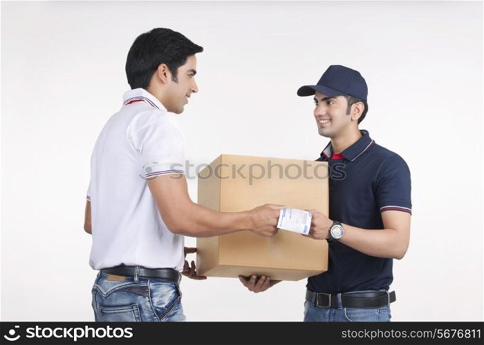 Delivery man giving package to customer against white background