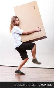 Delivery man holding a paper box.. Removal service and delivery concept. Young male guy postal courier holding big very heavy cube package carton.