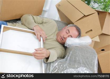 delivery man laying on floor covered in cardboard boxes