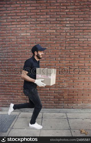 delivery man running with parcel front brickwall