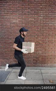 delivery man running with parcel front brickwall