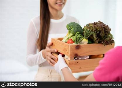 Delivery man sending wooden box of fresh organic fruits and vegetable