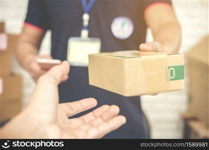 delivery man smiling and holding a cardboard box