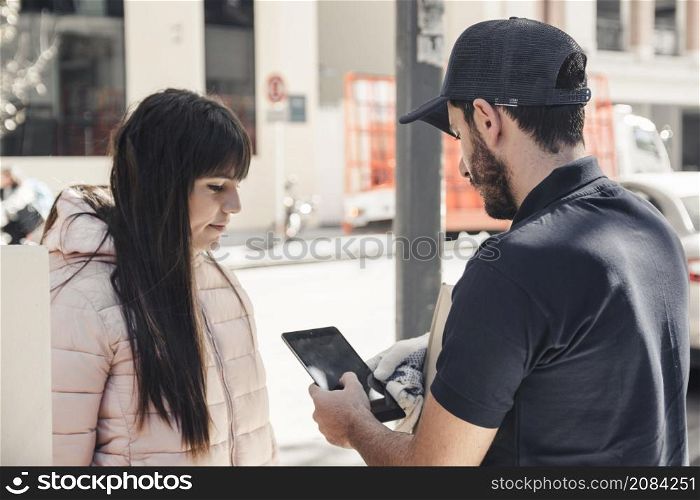 delivery man using digital tablet near female customer
