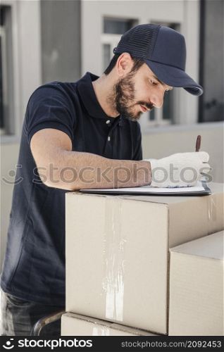 delivery man writing clipboard stacked cardboard boxes