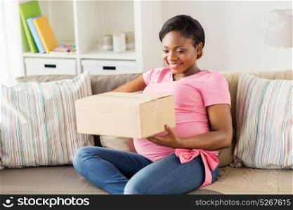 delivery, people and pregnancy concept - happy pregnant african american woman with parcel box at home. happy pregnant woman with parcel box at home