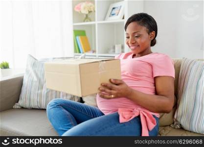 delivery, people and pregnancy concept - happy pregnant african american woman with parcel box at home. happy pregnant woman with parcel box at home