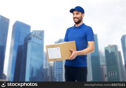delivery service, mail, people, logistics and shipping concept - happy man with parcel box over singapore city skyscrapers background. happy delivery man with parcel box