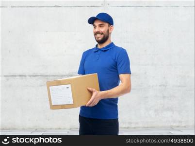 delivery service, mail, people, logistics and shipping concept - happy man with parcel box over gray concrete wall background. happy delivery man with parcel box