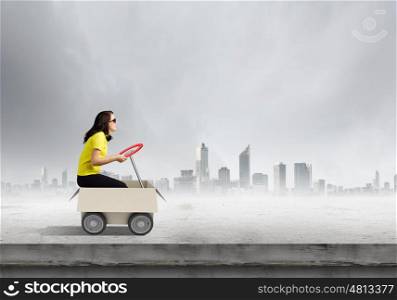 Delivery service. Young funny woman riding in carton box