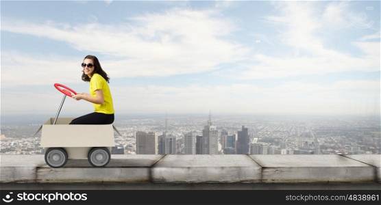 Delivery service. Young funny woman riding in carton box