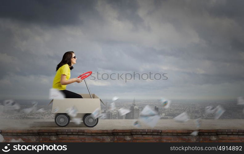 Delivery service. Young funny woman riding in carton box