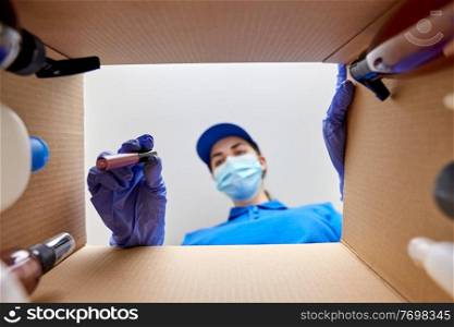delivery, shipping and pandemic concept - woman in protective medical mask and gloves packing parcel box with cosmetics and beauty products. woman in mask packing parcel box with cosmetics