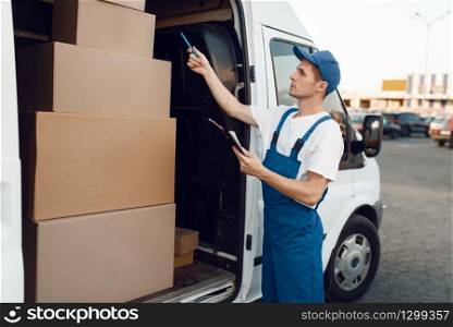 Deliveryman in uniform check boxes in the car, delivery service. Man standing at cardboard packages in vehicle, male deliver, courier or shipping job